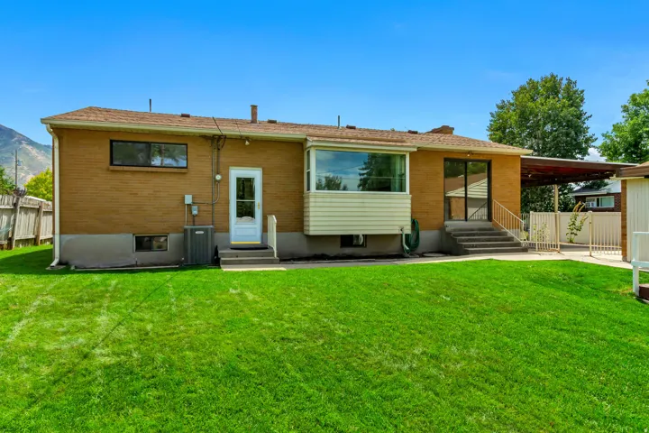 Expansive grassy yard with a brick exterior, a bay window, and a covered patio area