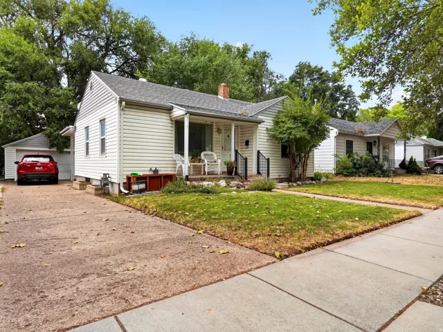 White siding exterior with a covered porch, detached garage, and concrete driveway