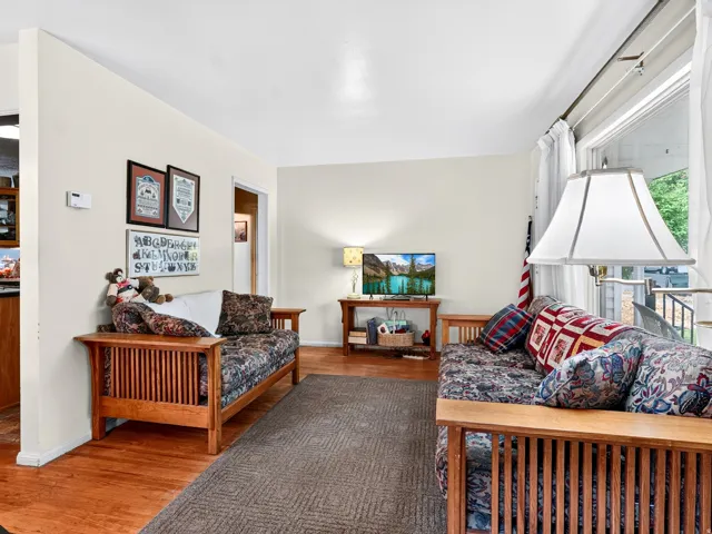 Hardwood-style flooring, light neutral wall paint, and a large window with sheers