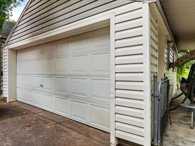 White paneled garage door with horizontal siding exterior