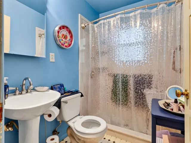 Pedestal sink, wall-mounted mirror, and white toilet
