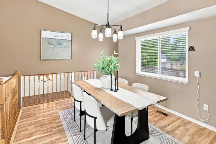 Vaulted ceiling, wood-finish flooring, white window blinds, and natural light from the window