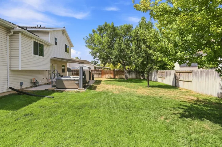 Expansive backyard featuring a lush lawn, mature trees, and a wooden privacy fence