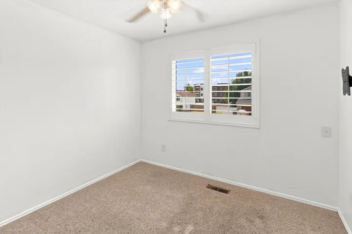 Bedroom #2.  White custom shutters shutters.  Ceiling fan.