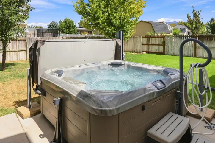 Bubbling hot tub on a concrete patio with privacy screen that can be opened.