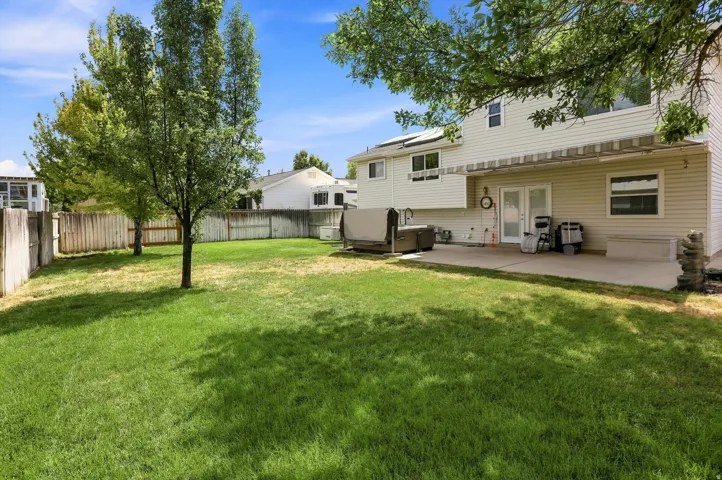 Expansive backyard.  Manicured lawn, established trees, privacy fencing, concrete patio, wall-mounted retractable awning