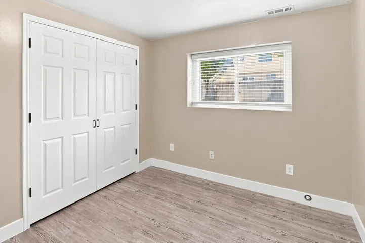 Bedroom #5.  Neutral tone walls, wood-finish flooring, and white trim