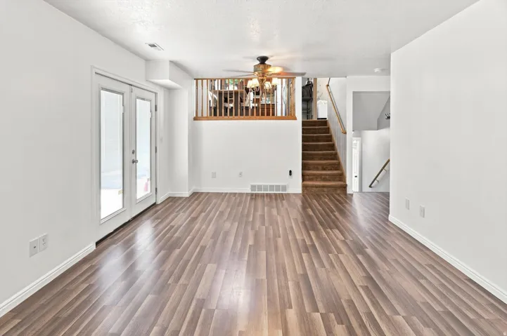 Wood-finish flooring throughout, bright white walls, and a Pella french doors to back yard