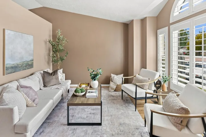 Vaulted ceilings, large arched window, bay box windows in a gorgeous design.  White shutters, neutral wall color, and wood-finish flooring