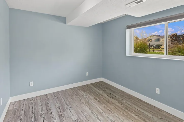 Bedroom #4.  Wood-finish flooring, a bright window, and light blue wall tones