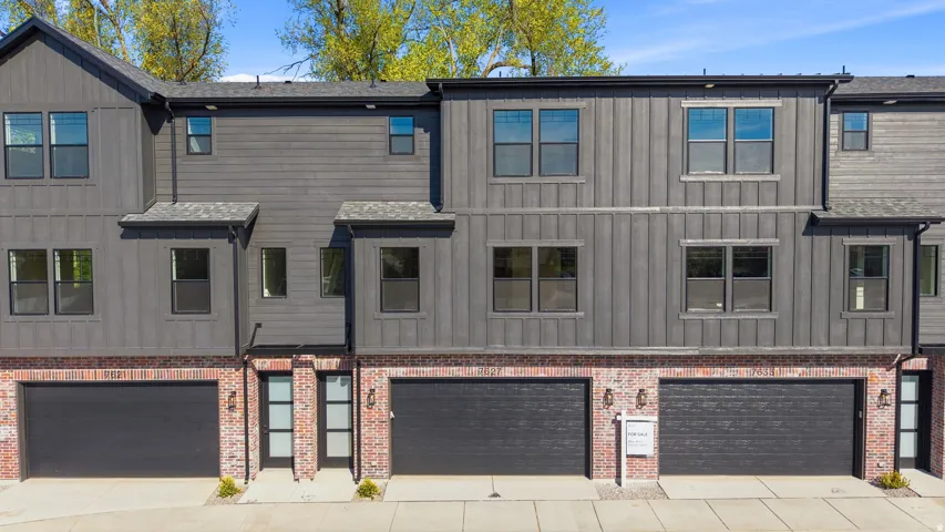 Modern townhome exterior with brick and vertical panel siding, multiple windows, and integrated garage access