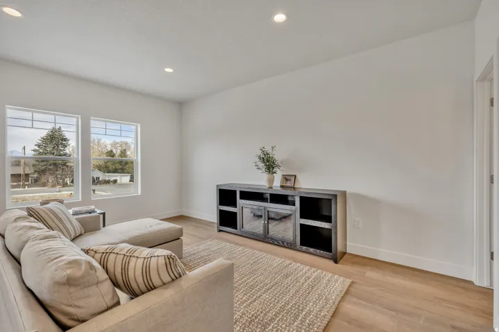 Recessed lighting illuminates the neutral-toned walls and wood-finish flooring
