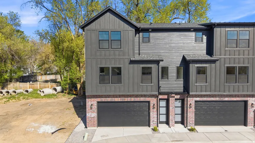 Townhome exterior featuring board and batten siding, brick accents, and a dark asphalt shingle roof