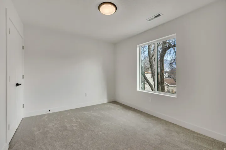 Neutral-toned carpet flooring, white walls, and a single window with a framed exterior