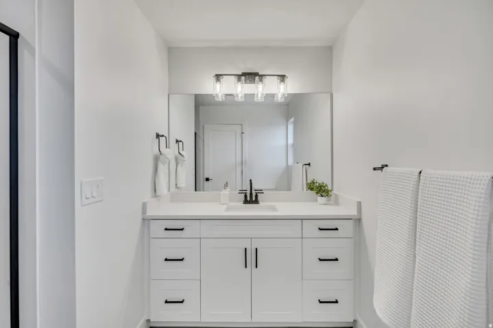 White vanity with integrated sink, polished countertop, and black hardware