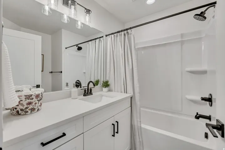 White vanity with shaker-style cabinetry, matte black hardware, and an integrated sink