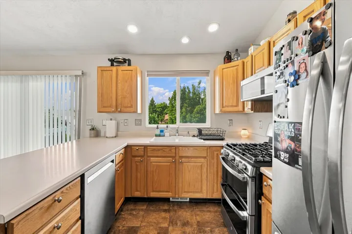 Kitchen featuring wood cabinetry, white countertops, a stainless steel gas range, and a stainless steel refrigerator