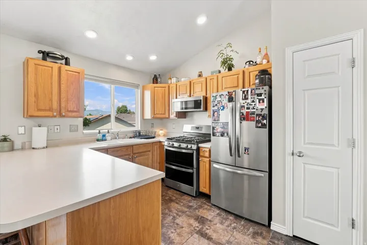 Kitchen featuring wood cabinetry, light-toned countertops, stainless steel appliances, and recessed lighting