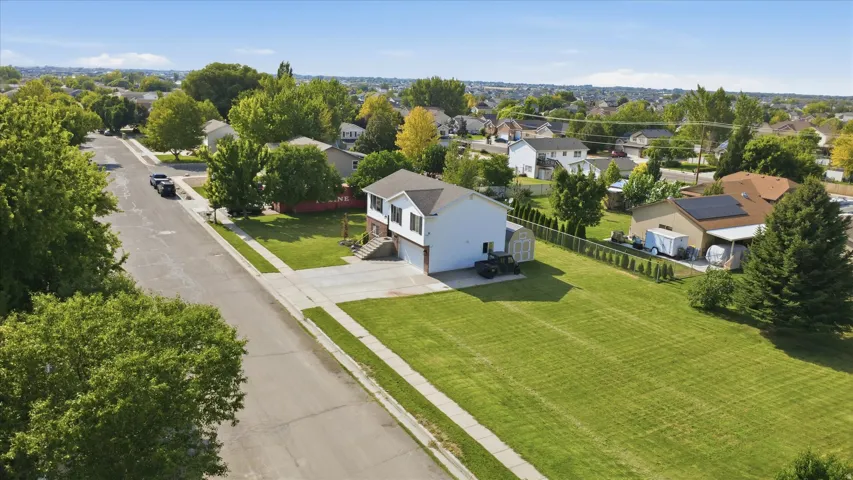 Expansive grass lawn, concrete driveway, two-story residence, side-entry garage, and a chain-link fence