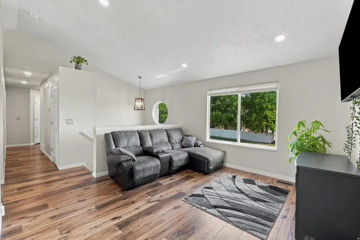 Vaulted ceiling with recessed lighting, wood-finish flooring, and a large picture window