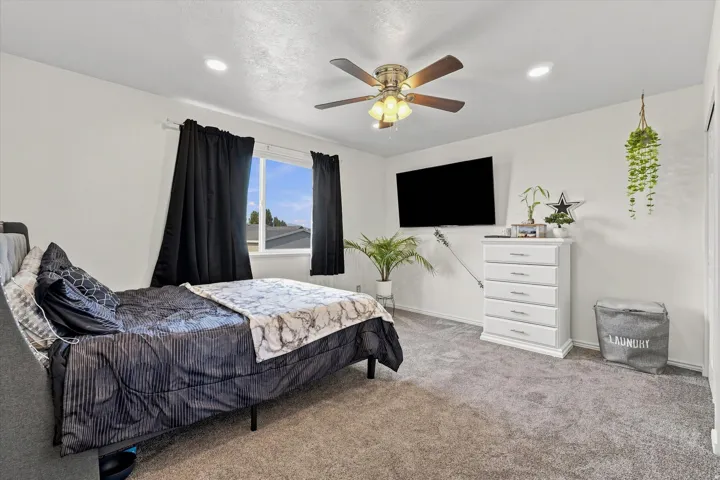 Recessed ceiling lighting, ceiling fan with integrated light fixture, carpet flooring, and a window with dark drapery