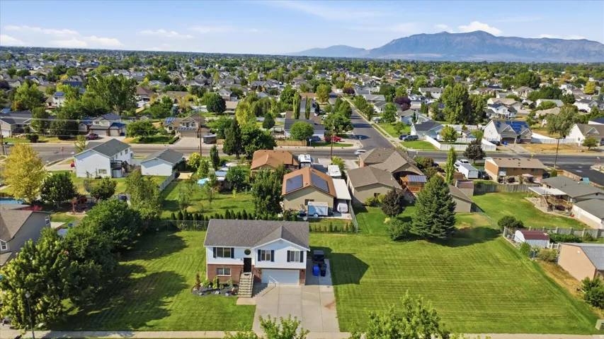 Split-level home featuring a two-car garage, manicured front lawn, and mature trees