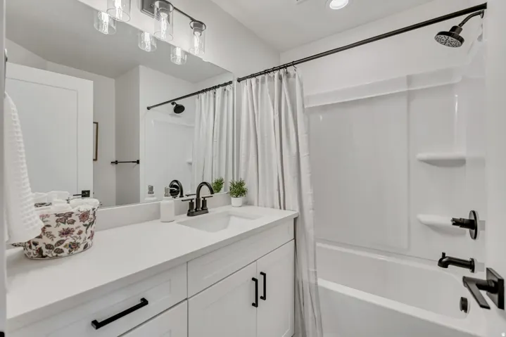 Spa-inspired bathroom featuring a white vanity with dual sinks, quartz countertop, and matte black hardware