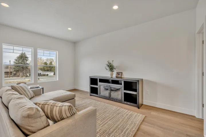Bright, open living space featuring hardwood flooring, recessed ceiling lighting, and expansive windows framing natural landscape views