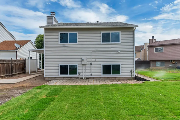 Rear exterior with a paver patio and a partially covered walkway