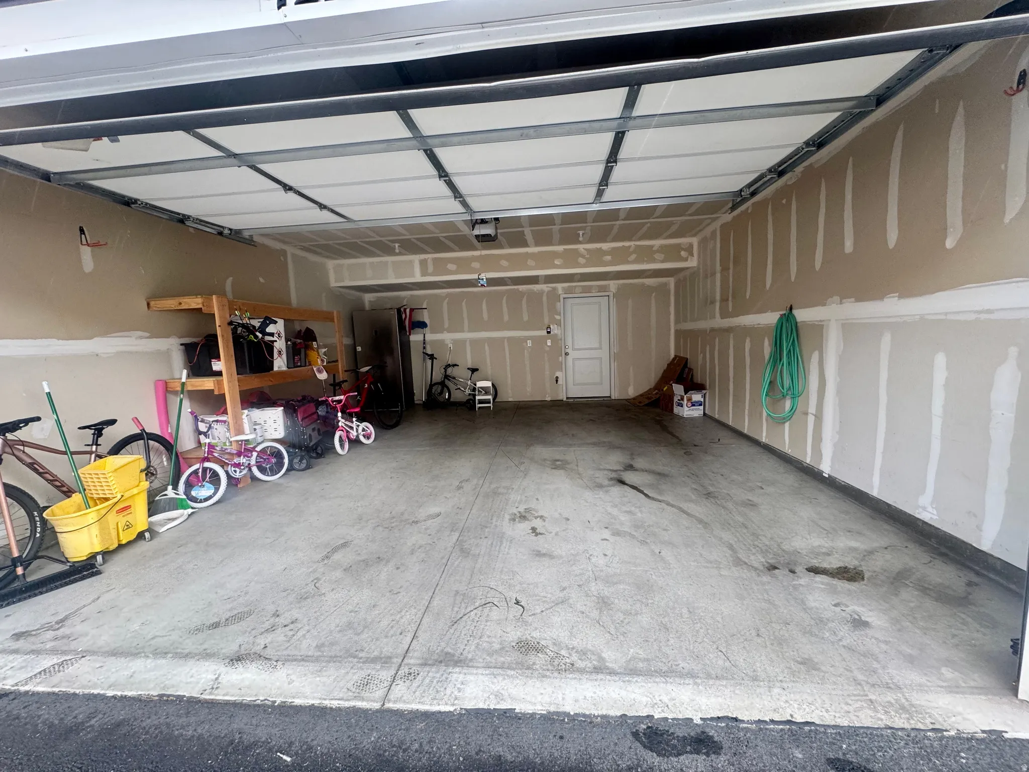 Spacious garage with an overhead door, concrete flooring, and an interior access door
