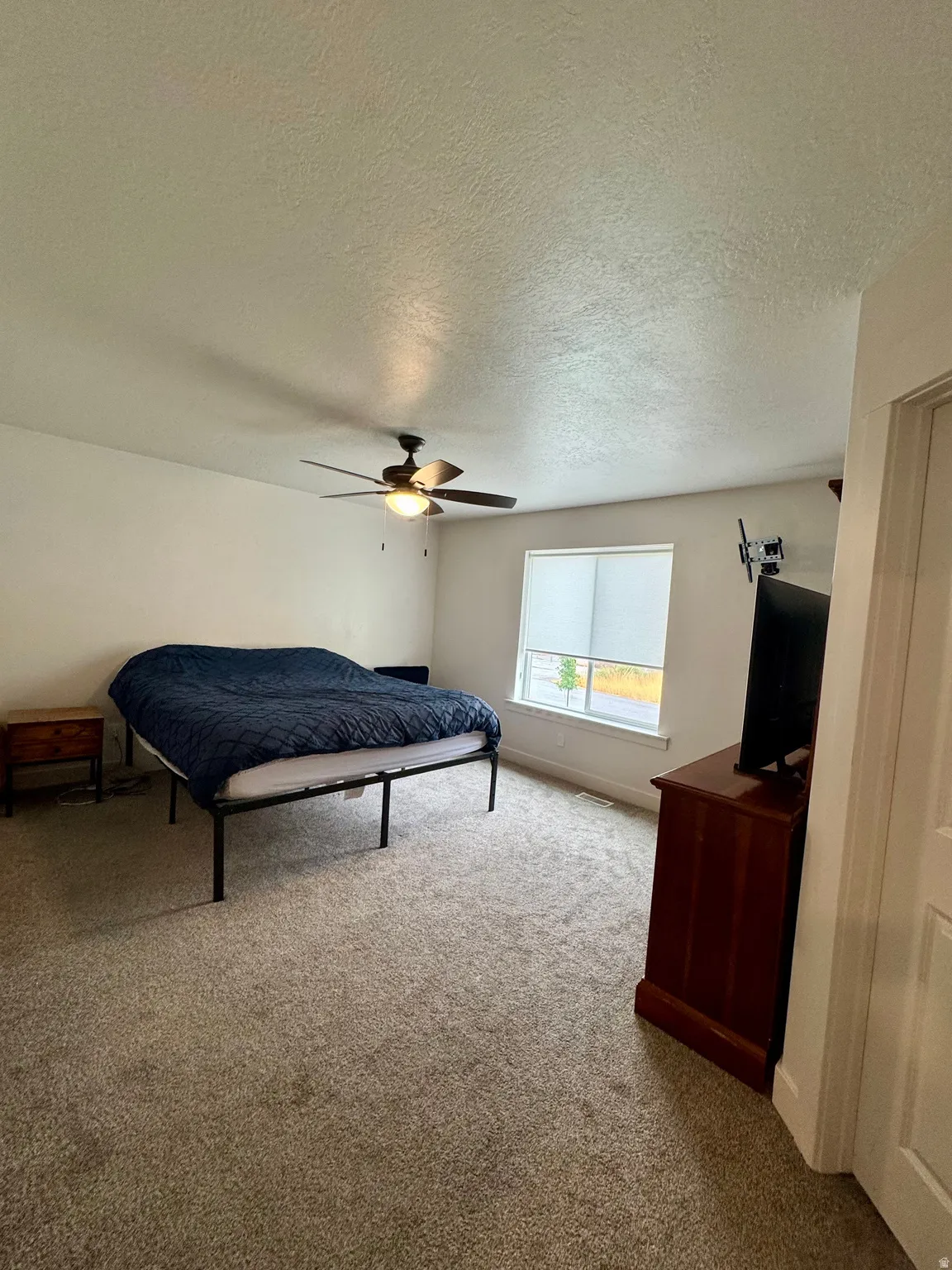 Plush carpet flooring, integrated ceiling fan with lighting, and a window with blinds