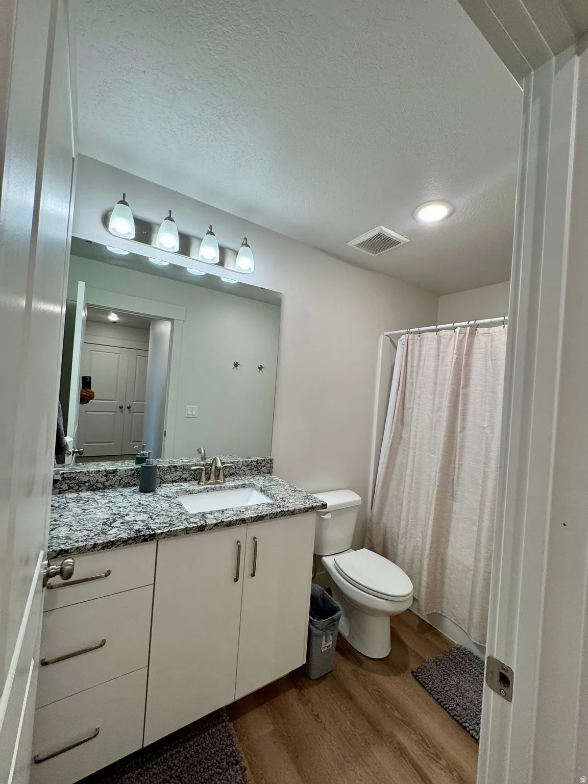 Vanity with a granite countertop, undermount sink, and brushed nickel faucet
