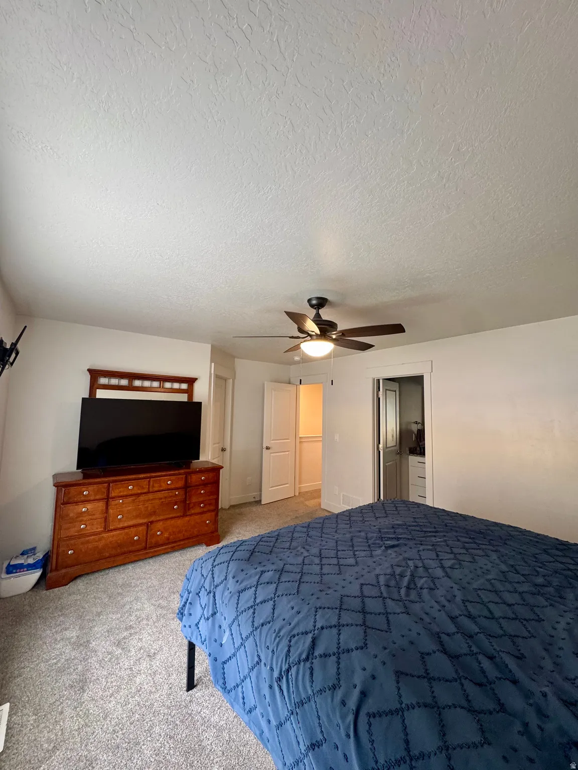 Carpeted bedroom with a ceiling fan, white walls, and white trim
