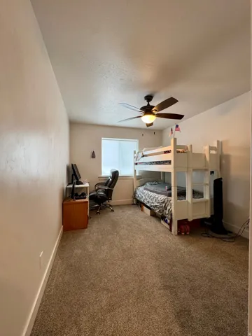 Carpeted flooring, a window with blinds, and a ceiling fan with integrated lighting