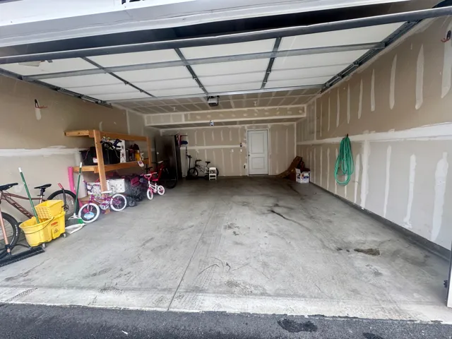 Spacious garage with an overhead door, concrete flooring, and an interior access door