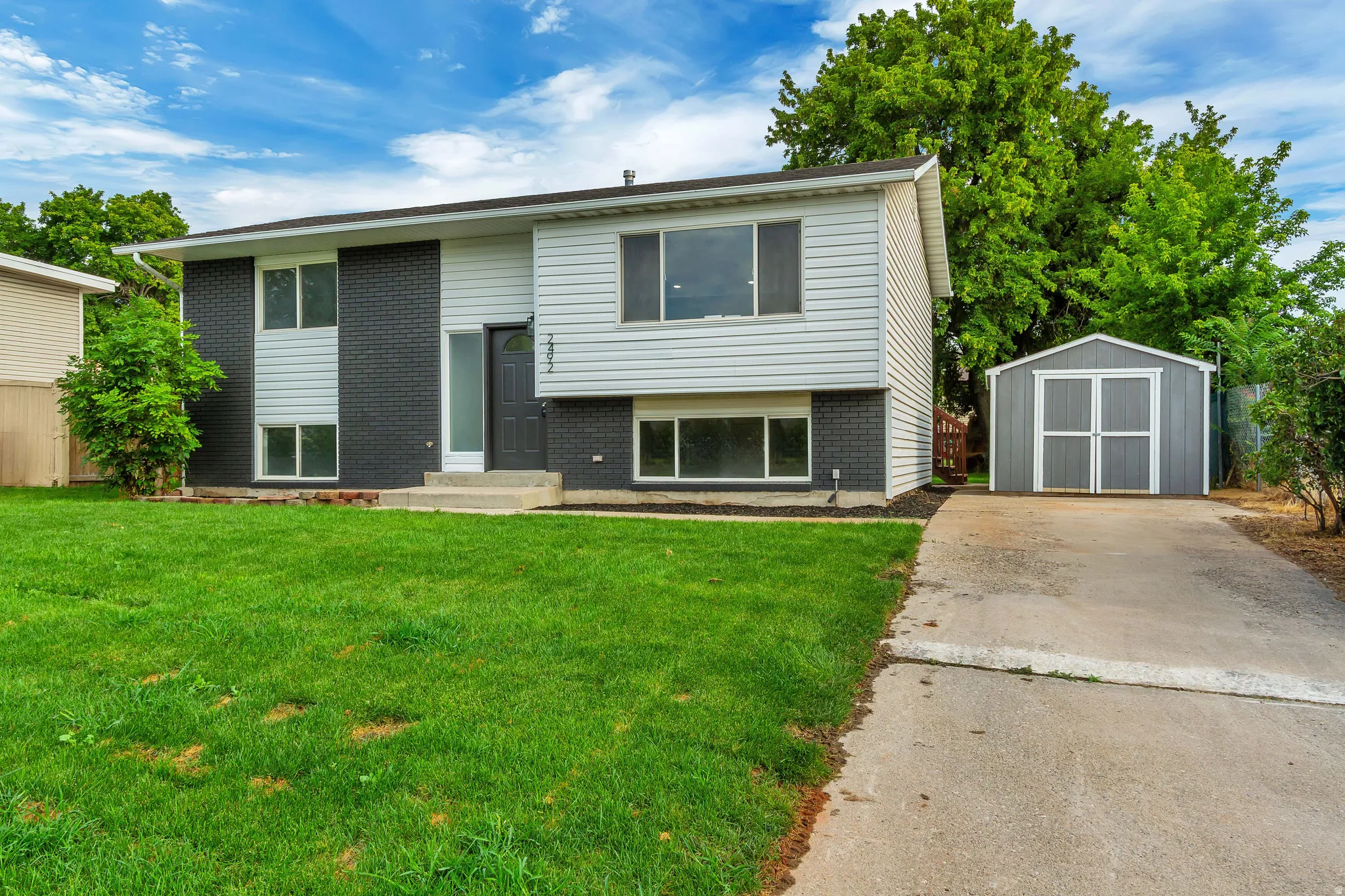 Two-story residence with a gray brick and light siding exterior, featuring multiple windows