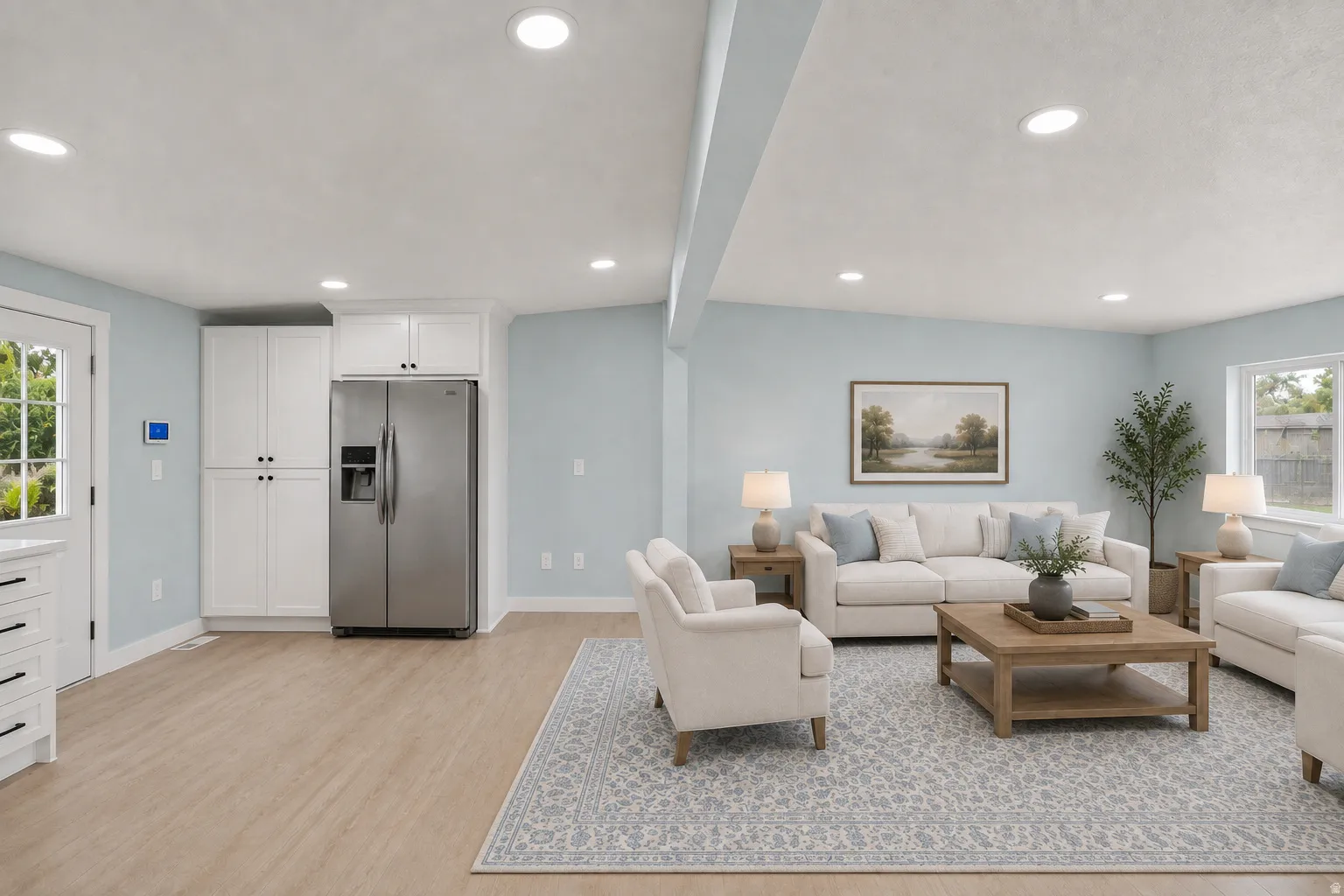 Recessed lighting, wood-finish flooring, white cabinetry, stainless steel refrigerator, and a glass-paned door