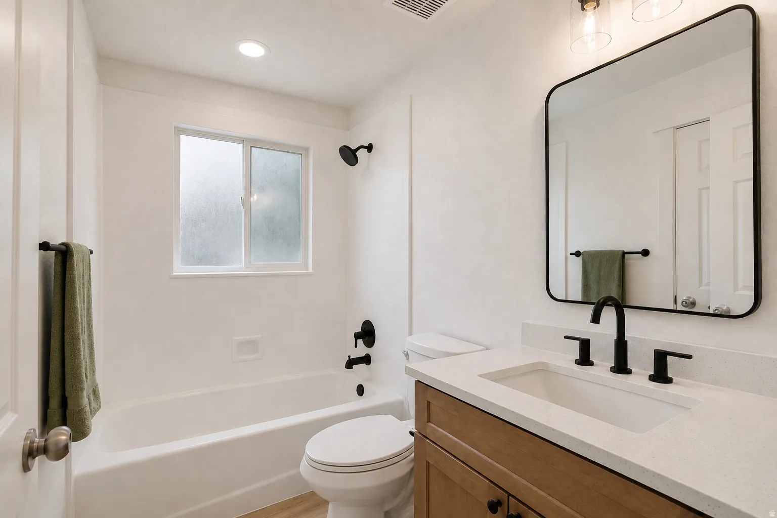 Bathroom featuring a wood-finish vanity, light countertop, undermount sink, and matte black fixtures