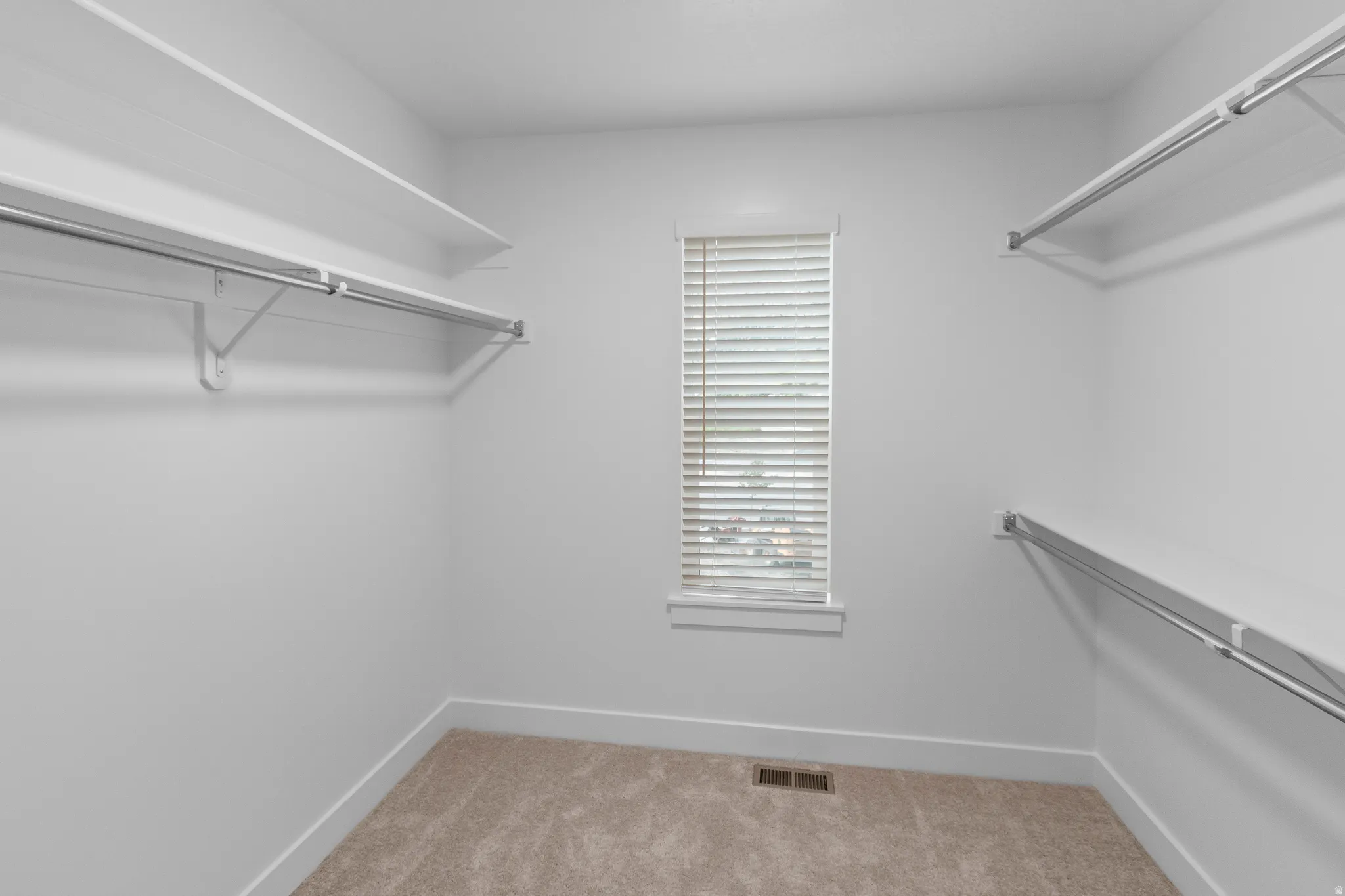 Carpeted flooring, window with blinds, and white wire shelving