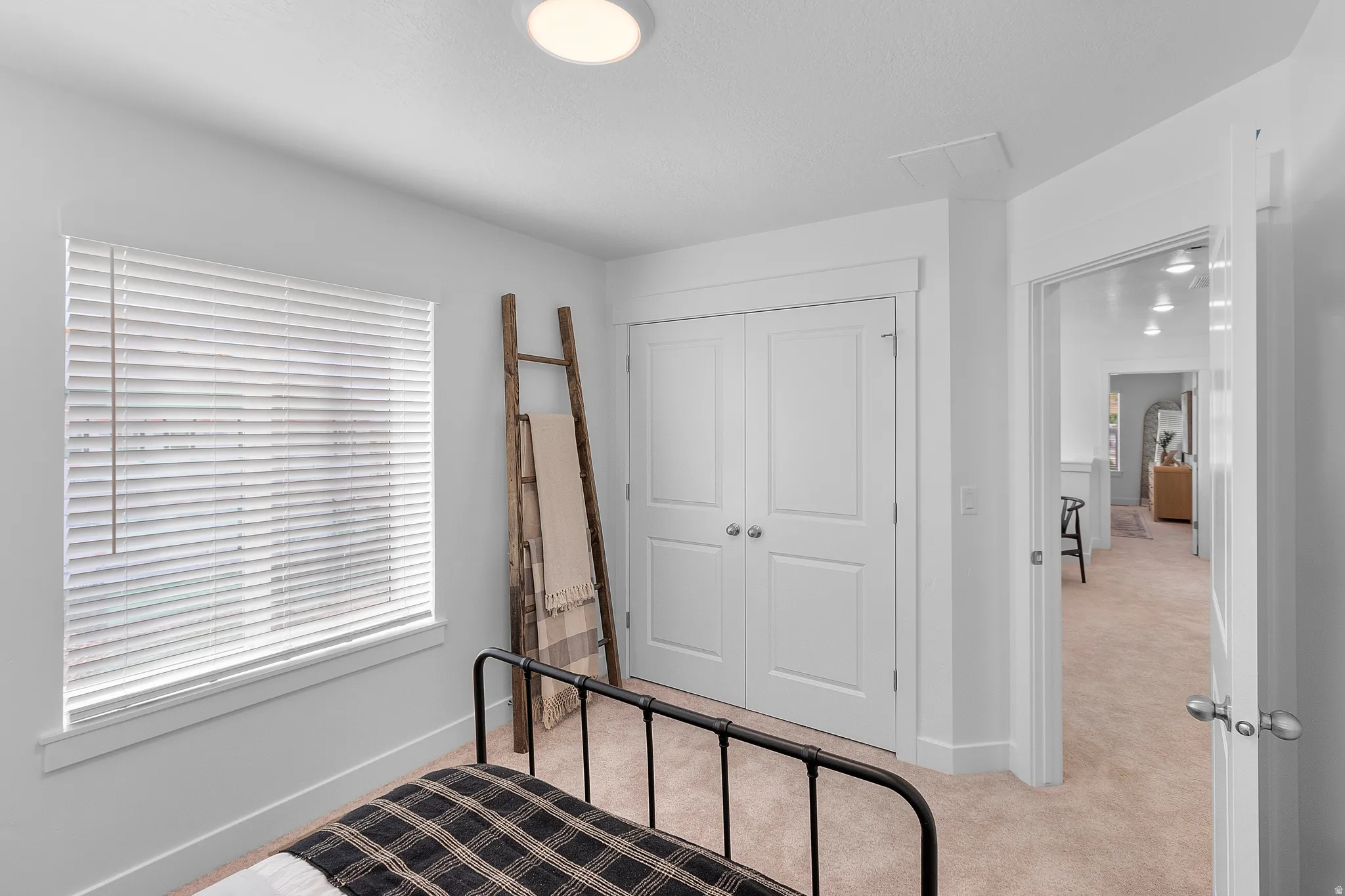 White walls, neutral carpet, and a window with white blinds