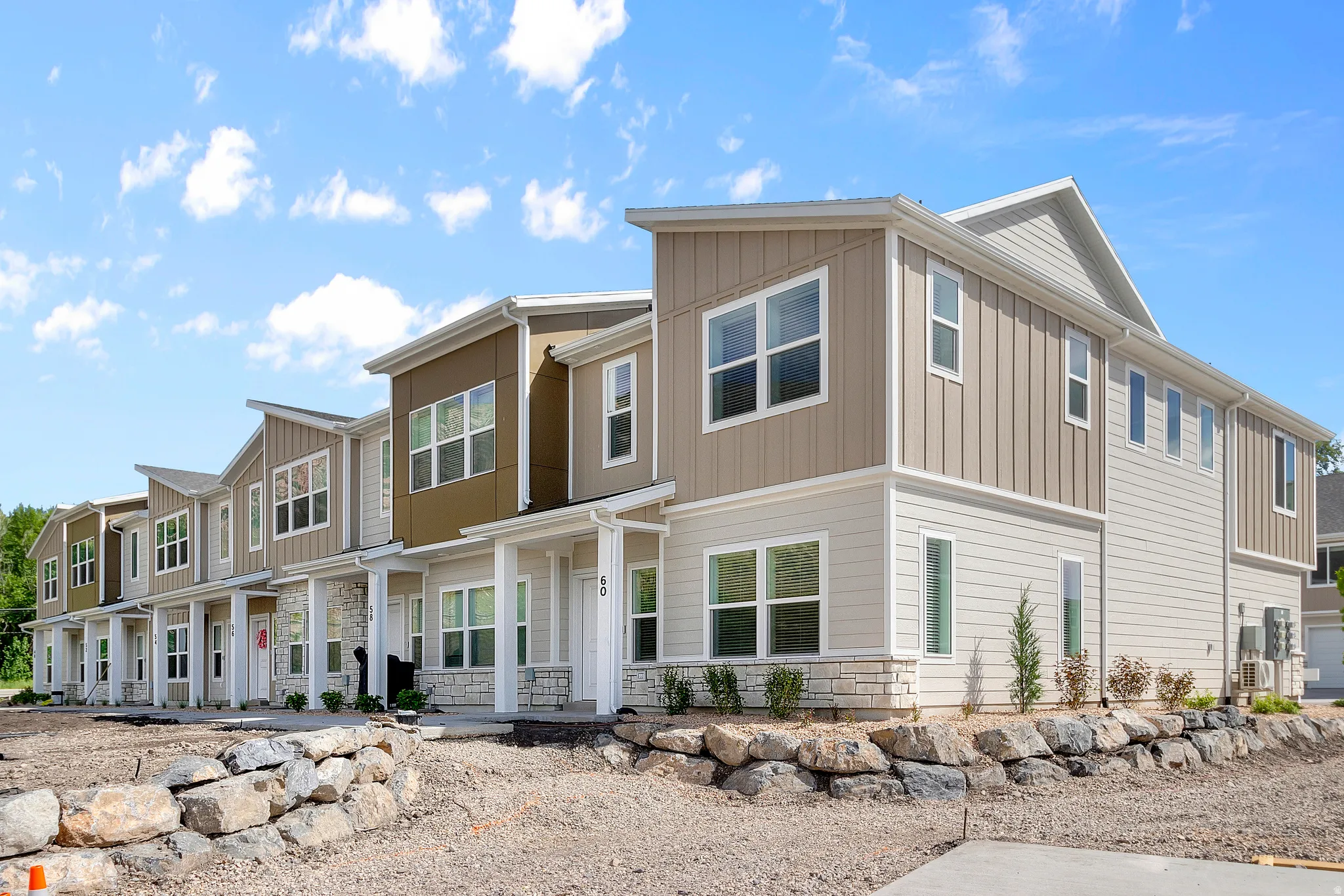 Modern multi-level exterior with vertical and horizontal siding, stone veneer accents, multiple windows, and a covered entry