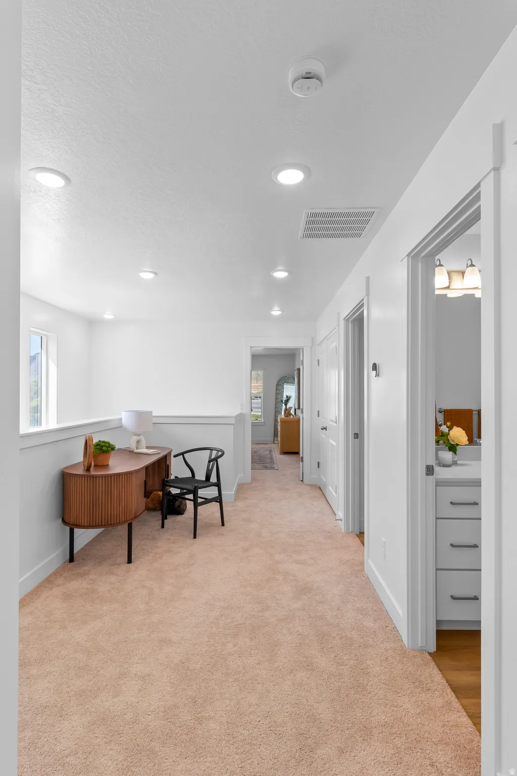 Recessed ceiling lighting, light-toned carpeting, white painted walls, white trim, and a built-in half-wall