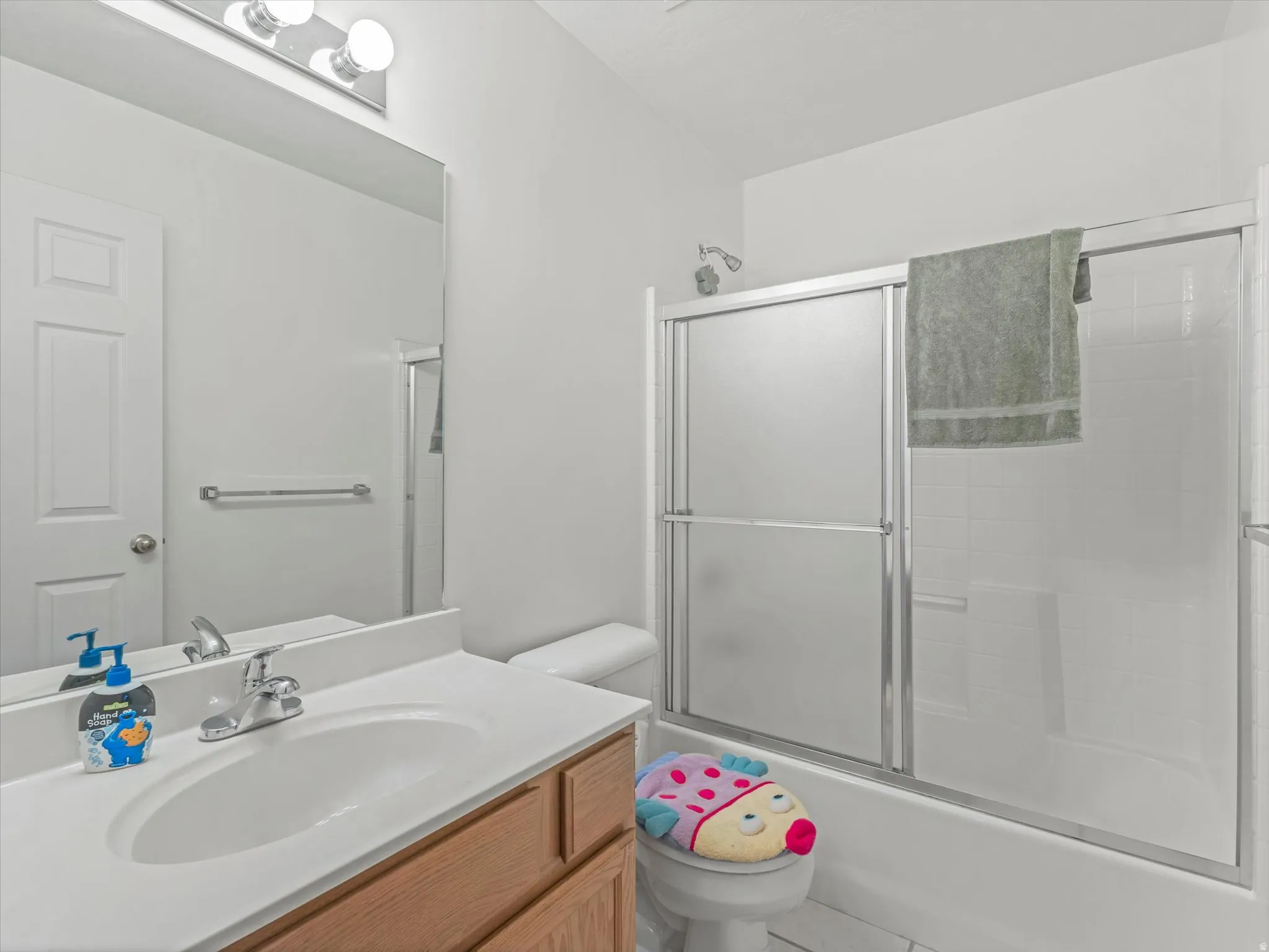 Vanity with an integrated sink, polished chrome faucet, wood-finish cabinetry, built-in mirror, and overhead vanity lighting