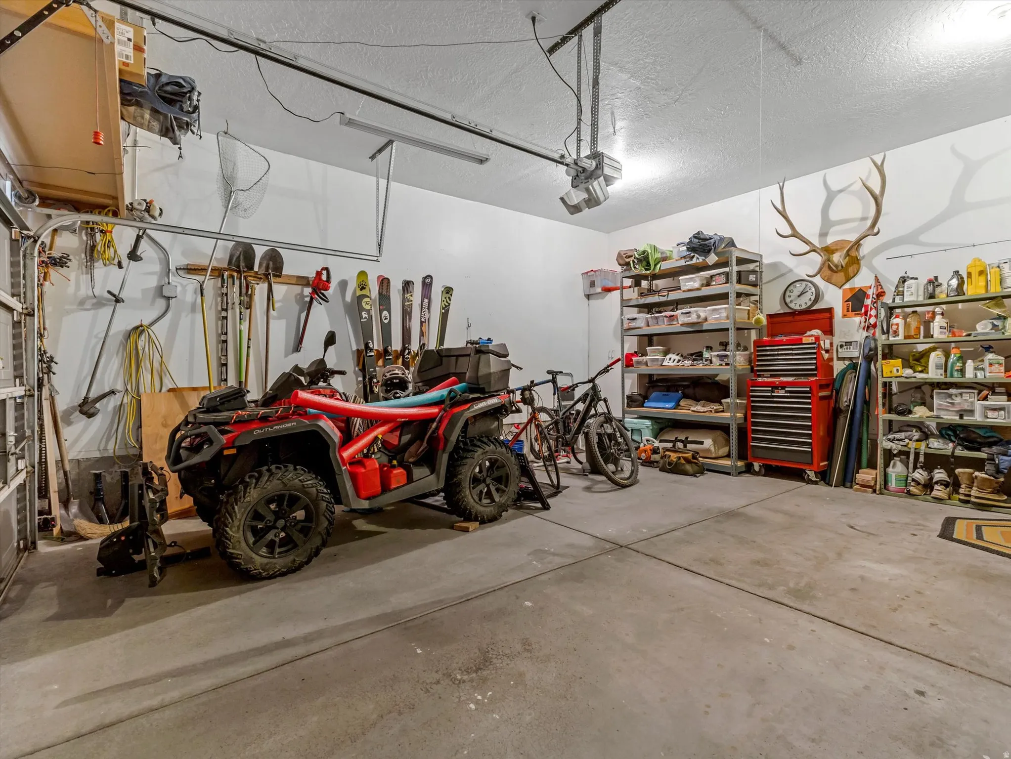 Garage with concrete flooring, overhead fluorescent lighting, and built-in shelving units