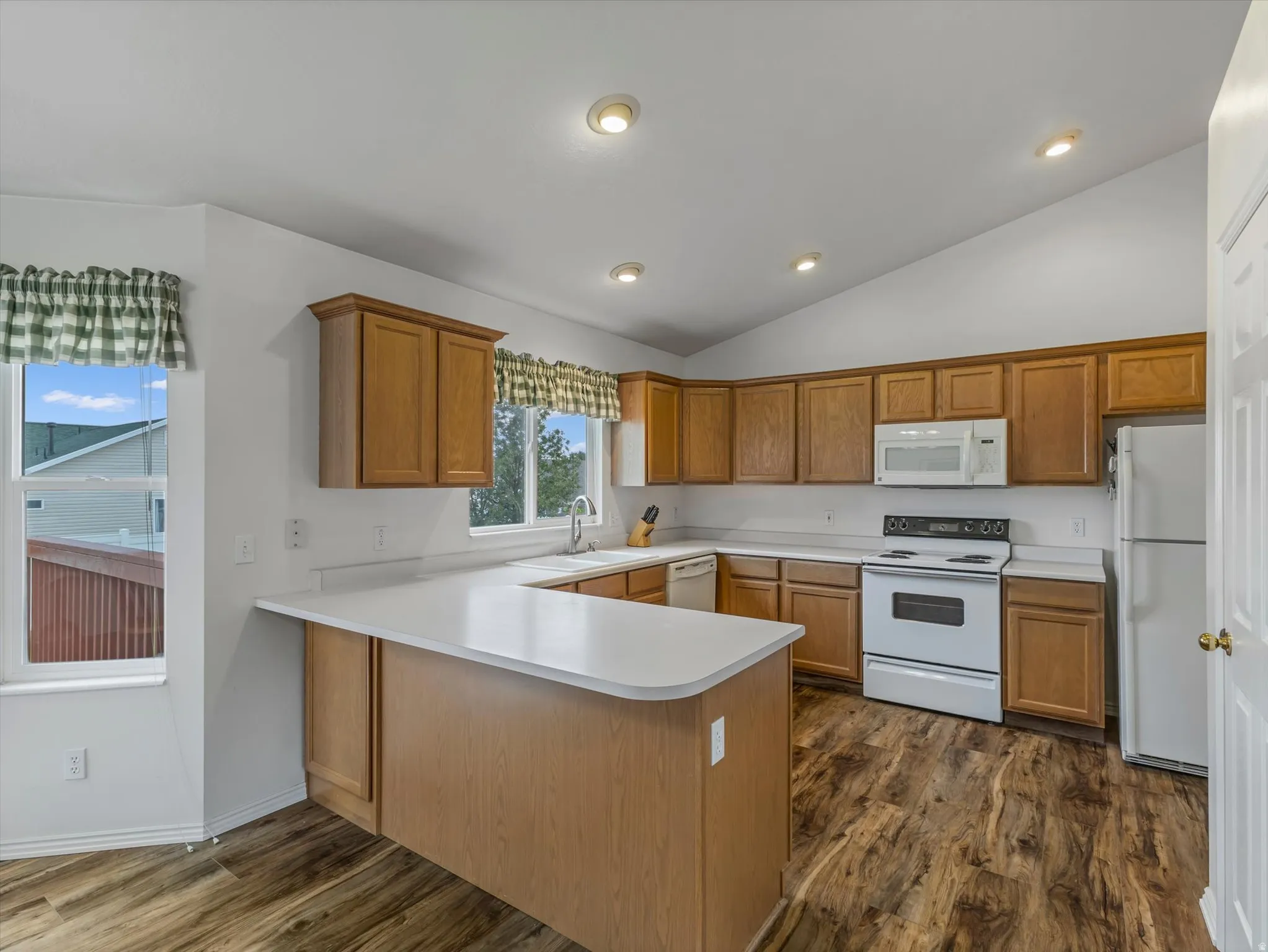 Kitchen with wood-finish flooring, vaulted ceiling, recessed lighting, and wood cabinetry