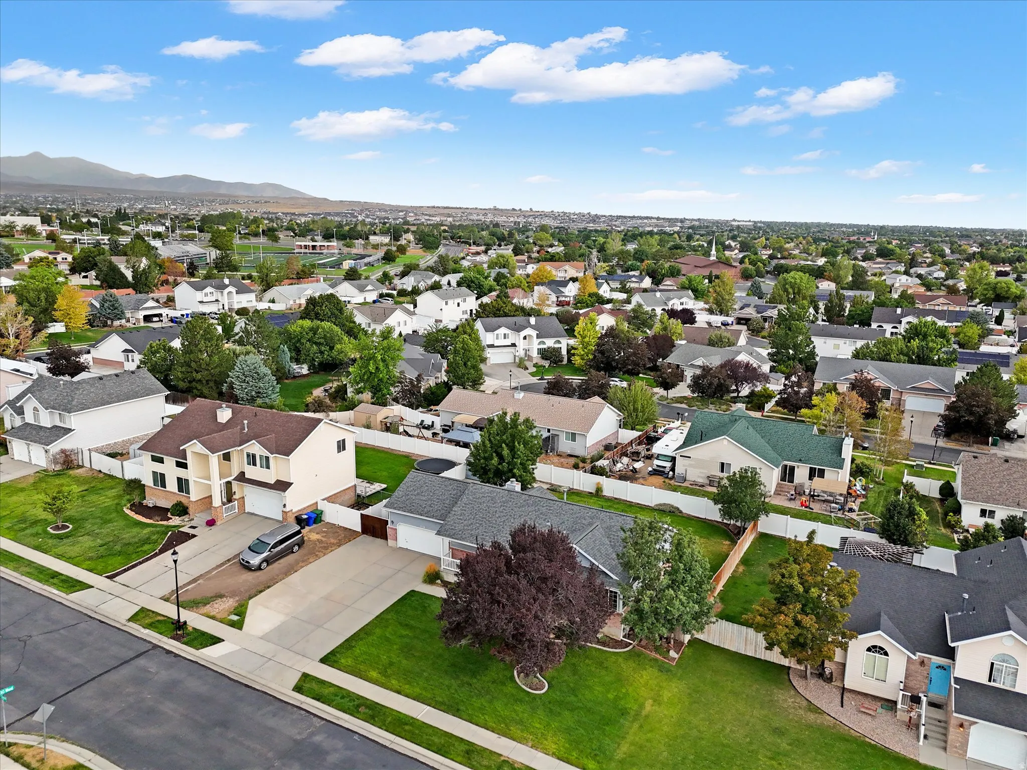 Expansive suburban neighborhood featuring numerous single-family homes, mature trees, and mountainous scenery