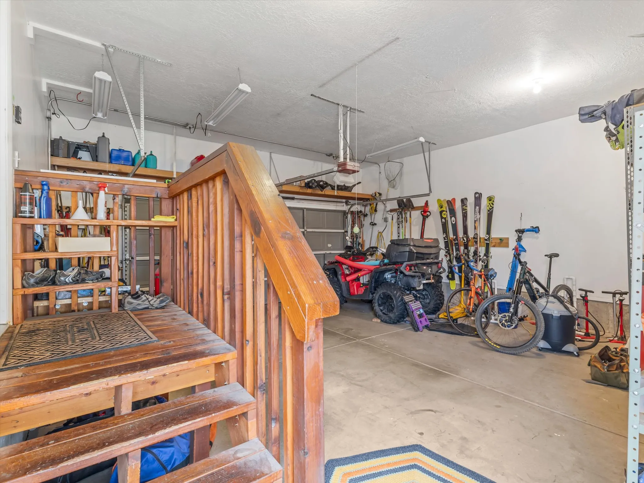 Attached garage featuring concrete flooring, built-in shelving, and overhead lighting