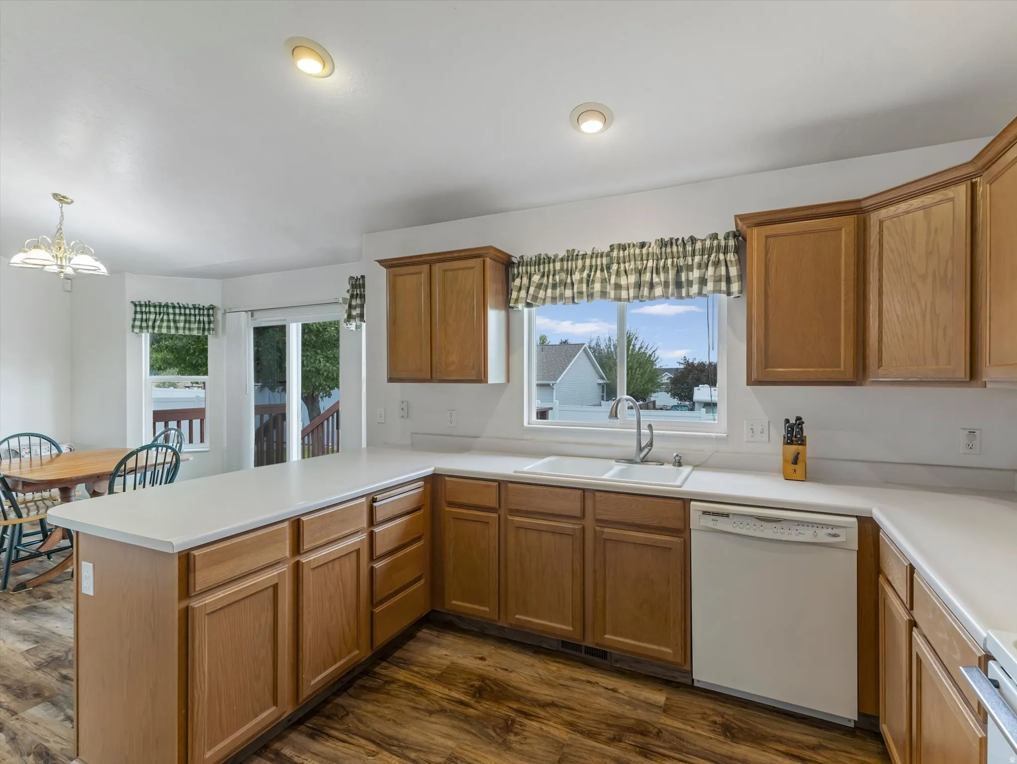 Kitchen featuring wood-finish flooring, light wood cabinetry, white countertops, and a double-basin sink