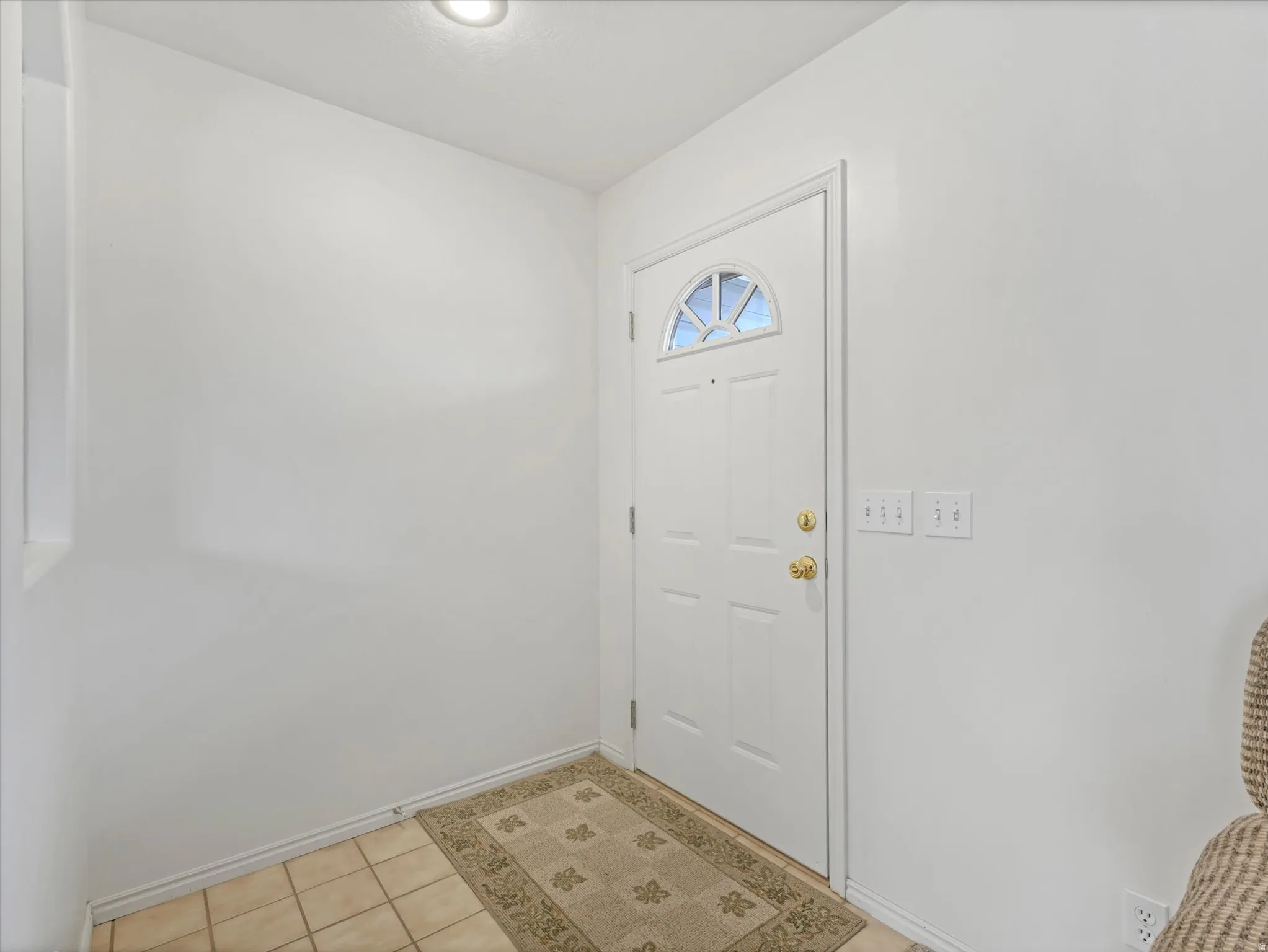 Entryway with white walls, recessed ceiling lighting, a white door with an arched window, and tile flooring