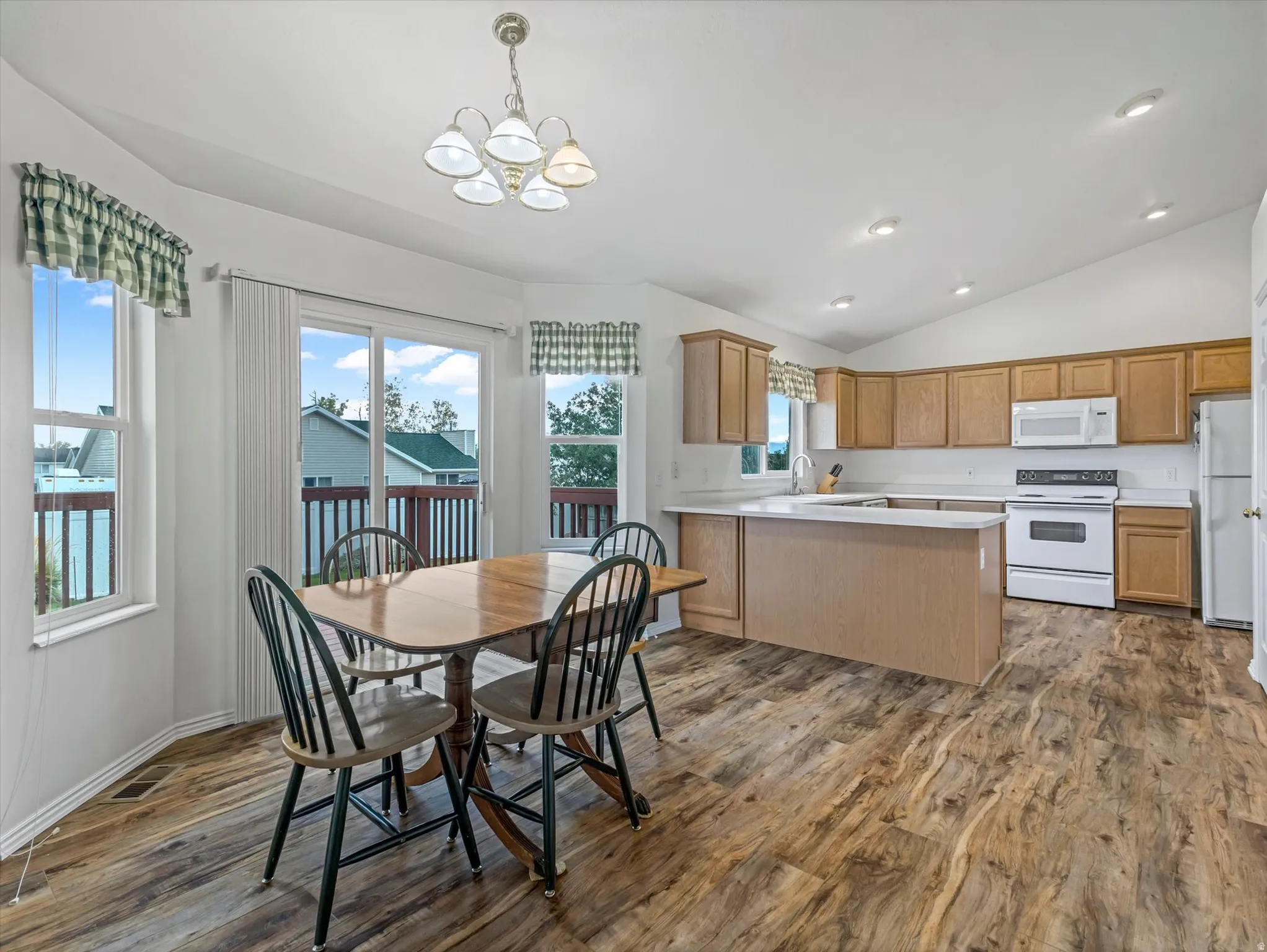 Kitchen featuring wood-finish flooring, light-toned cabinetry, white countertops, and white appliances